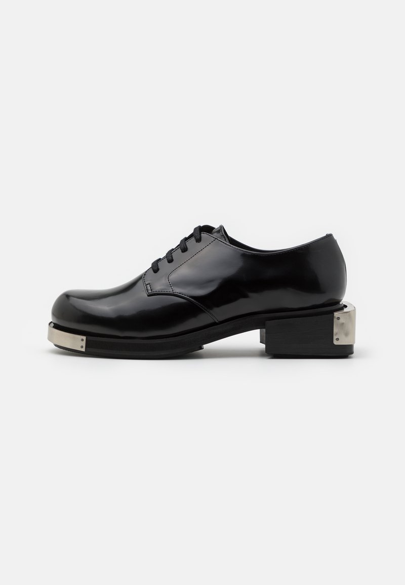 Scarpa in pelle verniciata nera con punta arrotondata, design con lacci e tacco basso a blocco con dettagli metallici sul retro.