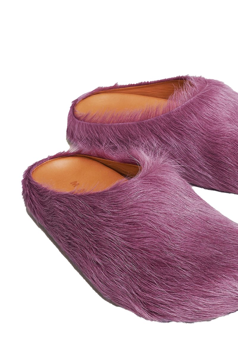 Zoccoli viola in pelliccia, con bordi arrotondati e una soletta in pelle liscia, che mostrano un esterno morbido e strutturato.