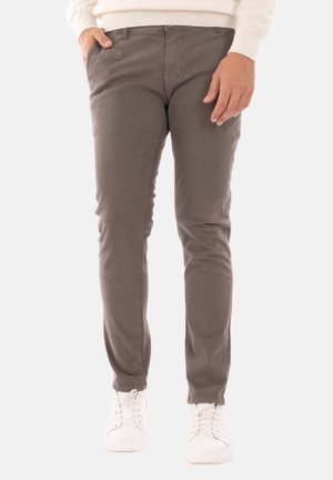 Pantaloni in cotone di colore marrone tenue, dal taglio slim, con due tasche frontali e una vita pulita, abbinati a sneakers bianche.