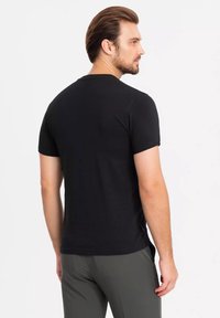 Sort kortærmet T-shirt lavet af blødt stof, med rund hals og en tætsiddende pasform, med en glat tekstur og en ensfarvet ryg.