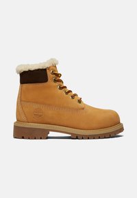 Tansfarbenen Leder-Ankle-Boot mit einem Shearling-Kragen, braunen Wildleder-Akzenten, goldenen Ösen und einer robusten Gummi-Sohle, die ein texturiertes Profilmuster aufweist.