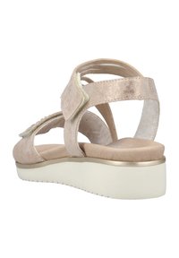 Light pink suede sandal with adjustable strap, open back design, padded footbed, and a white, textured wedge sole with gold accent.