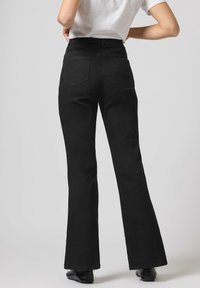 Jeans negros acampanados de cintura alta, confeccionados en una tela suave. Cuentan con dos bolsillos traseros y un diseño limpio, adecuado para diversos atuendos.