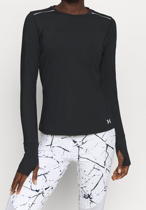 Personne portant un haut de sport noir à manches longues avec des trous pour les pouces et des leggings blancs avec un motif marbré noir.