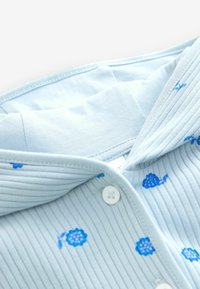 Light blue ribbed shirt featuring small blue floral patterns, with a collar and white buttons. Soft cotton texture.