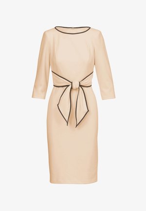 Robe beige clair avec manches trois-quarts, taille cintrée ornée d'un lien noir, et une silhouette élégante et ajustée.