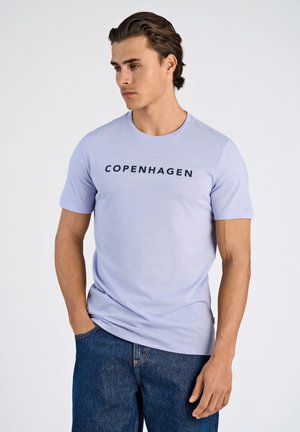 T-shirt court à manches courtes de couleur violet clair avec "COPENHAGUE" et "LINDBERGH" imprimés en noir sur le devant. Tissu doux avec un col rond.