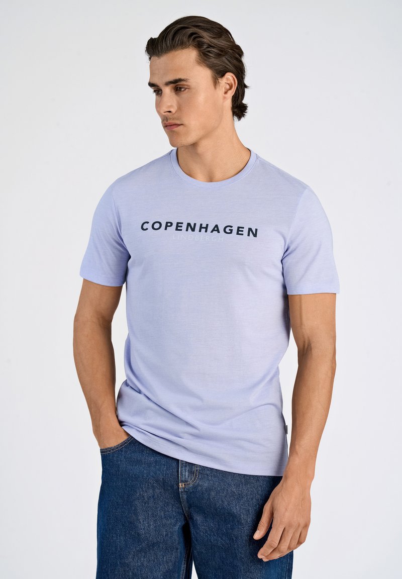 Vaaleanlila lyhythihainen t-paita, jossa rinnassa on mustana painettuna "COPENHAGEN" ja "LINDBERGH". Pehmeää kangasta, jossa pyöreä pääntie.