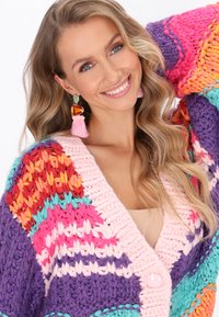 Stickad cardigan med livfulla färger: lila, rosa, röd, orange och teal. Tjock textur med djup V-ringning och stora knappar.