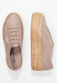 Beiga dukskor med en strukturerad tyg, rund tå och en vävd jutesula. Har silveröglor och en varumärkesetikett.