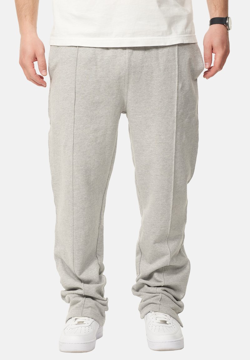 Hellgraue Sweatpants aus einem weichen Baumwollmix, mit seitlichen Nähten und elastischen Bündchen, kombiniert mit weißen Sneakers.