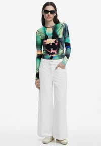 Tricou cu mânecă lungă, cu un model abstract multicolor, combinat cu pantaloni albi largi și pantofi deschiși. Material neted, design ajustat.