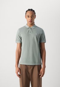 Lys grønn polo skjorte med krage, tre knapper og en liten brodert logo på brystet. Glatt stoff, korte ermer.