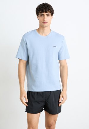 Lyseblå kortermet t-skjorte med strukturert stoff og en liten svart "BOSS"-logo på brystet, kombinert med svarte shorts.
