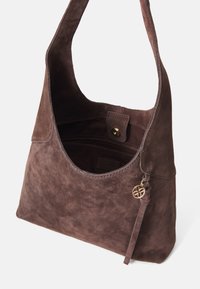 Braune Wildleder-Umhängetasche mit weicher Textur, großem Eingangsbereich und goldfarbenen Akzenten. Verfügt über einen Magnetverschluss und eine dekorative Quaste.