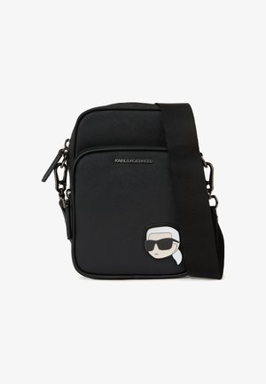 Sort crossover taske lavet af tekstureret materiale, der har en frontlomme med lynlås og et Karl Lagerfeld-logo med en tegneseriefigur i solbriller.
