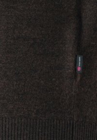 Dunkelbrauner Strickstoff mit geripptem Saum und einem kleinen schwarzen Etikett mit weißem und rosafarbenem Text auf der rechten Seite.