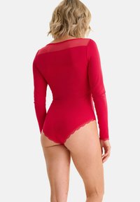 Body rouge à manches longues avec empiècement en mesh transparent, bordure en dentelle festonnée le long de la jambe et coupe ajustée pour une silhouette lisse.