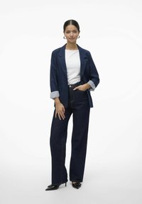 Tumesinise bleiser kahe nupuga, valge pluus, tume denim laiade jalgade püksid ja mustad terava ninaga kõrged kontsad, millel on pinstripe'iga varruka aktsent.