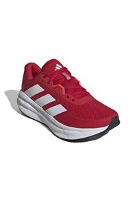 Red athletic shoe with breathable mesh upper, white three-stripe design, and rubber sole. Features laces and padded collar for support.