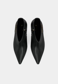 Stivaletti neri a punta, realizzati in pelle liscia, con chiusura a zip e design minimalista. Silhouette elegante e moderna, priva di motivi.