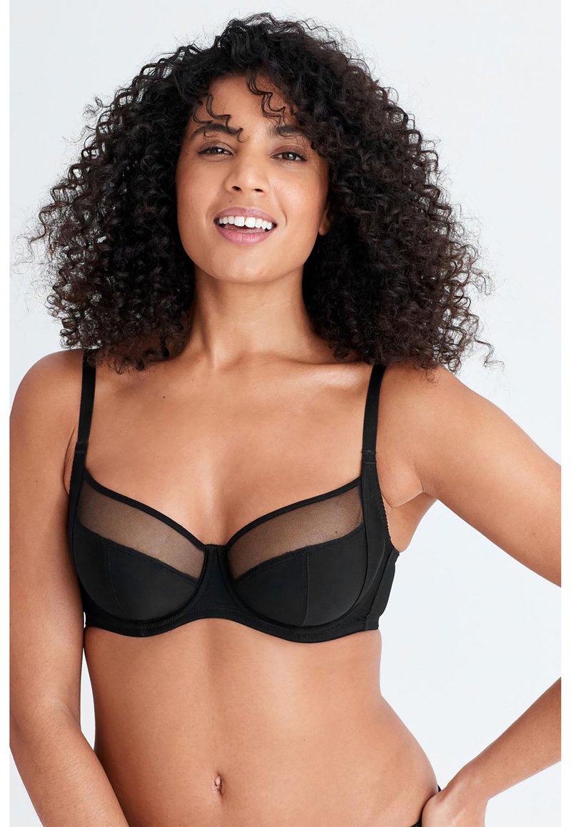 Soutien-gorge noir avec armatures, présentant des panneaux en tulle transparent, des bonnets structurés et des bretelles réglables. Tissu lisse avec un léger éclat.