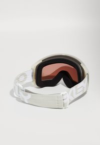 Skibriller med en gjennomsiktig ramme, rosa farget linse, svart skumputefor og en hvit justerbar stropp med logo.