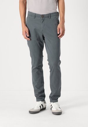 Grå bomulds chinos med en slim fit, der har en knaplukning, sidelommer og opsmøgede manchetter. Sammen med hvide og grå sneakers.