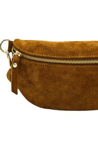 Sac en suède marron avec une forme arrondie, des accessoires zippés en or et une finition texturée. Dispose d'une boucle latérale et d'une attache de court strap.