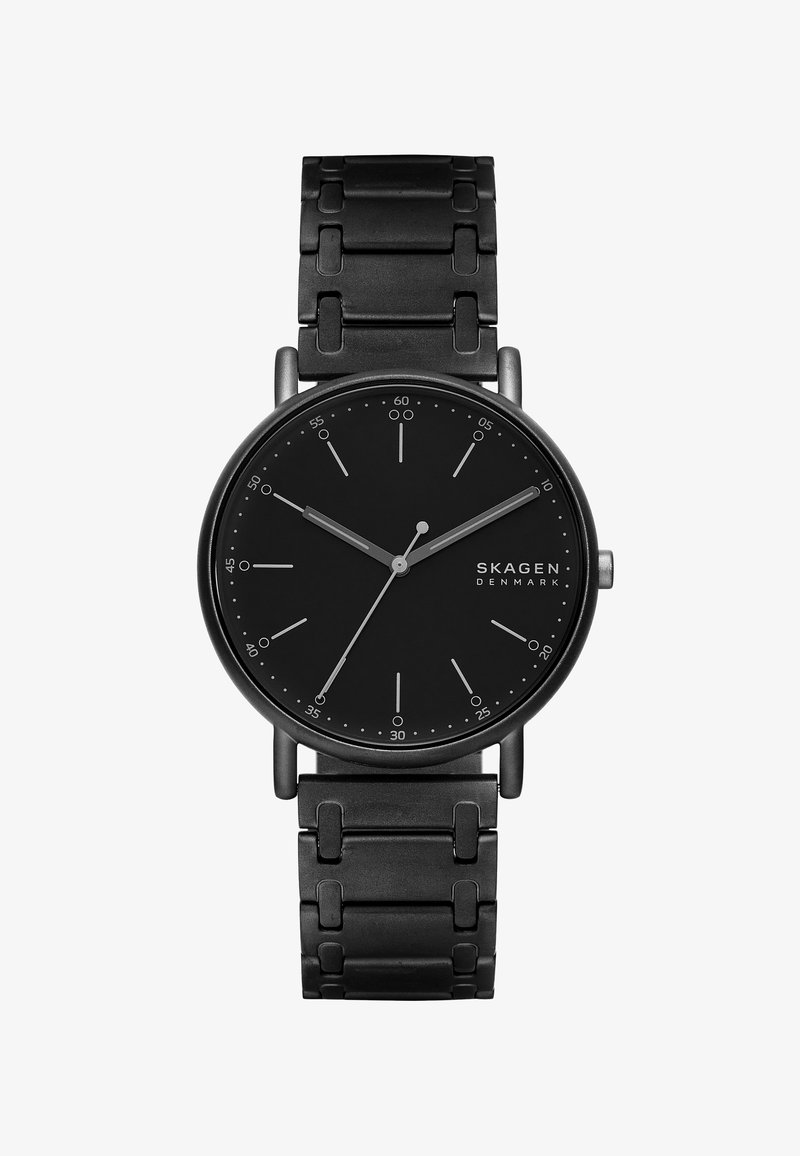 Musta roostevaba terasest kell ümmarguse näo, minimalistlike markerite ja kätega. Omab stiilset, tekstuuriga käevõru disaini.