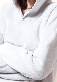 Cozy grey fleece pullover with a high collar, soft texture, and relaxed fit. Features a kangaroo pocket at the front and cuffed sleeves.