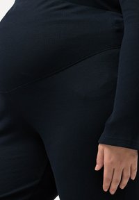 Mörkblå räfflade leggings har en figursydd design med en hög midja. Materialet verkar texturerat och framhäver en slät yta.