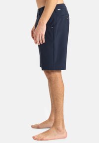 Marineblå shorts laget av lett stoff, med rett snitt, to sidelommer og en enkelt baklomme med knappelukking.