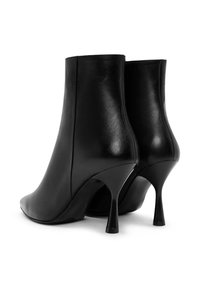 Zwarte leren enkellaarsjes met een puntige neus en een slanke silhouette, gekenmerkt door een smalle hoge hak. Glad textuur met minimale ontwerpdetails.