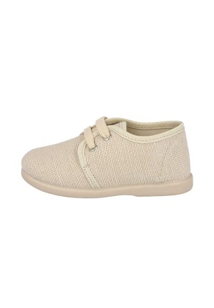 Zapato para niño pequeño de tela beige tejida con dos lazos de cordón, suela blanda y cuello acolchado, mostrado desde el lado exterior sobre fondo blanco.