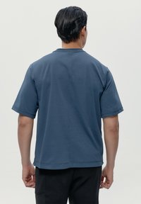 Mörkblå kortärmad skjorta med rak sidsöm och rund halsringning, tillverkad av mjukt tyg. Har minimal sömnad och en avslappnad passform.