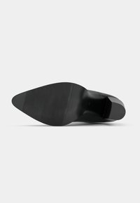 Sapato de salto alto preto com parte superior em couro liso, bico fino, salto quadrado e sola de borracha texturizada. Design limpo sem adornos.