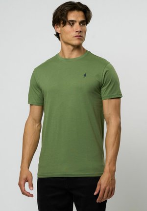 Green short-sleeve t-shirt made of cotton with a round neckline and a small navy logo accent on the chest. Black pants visible.