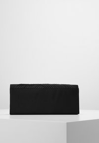 Černá psaníčko s měkkým textilním tělem a texturovaným tkaným horním detailem. Obdélníkový tvar, kompaktní design a minimalistický styl.