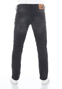 Jeans de mezclilla negra con corte recto, que cuentan con bolsillos traseros con costuras angulares y una etiqueta de cuero marrón en la cinturilla.