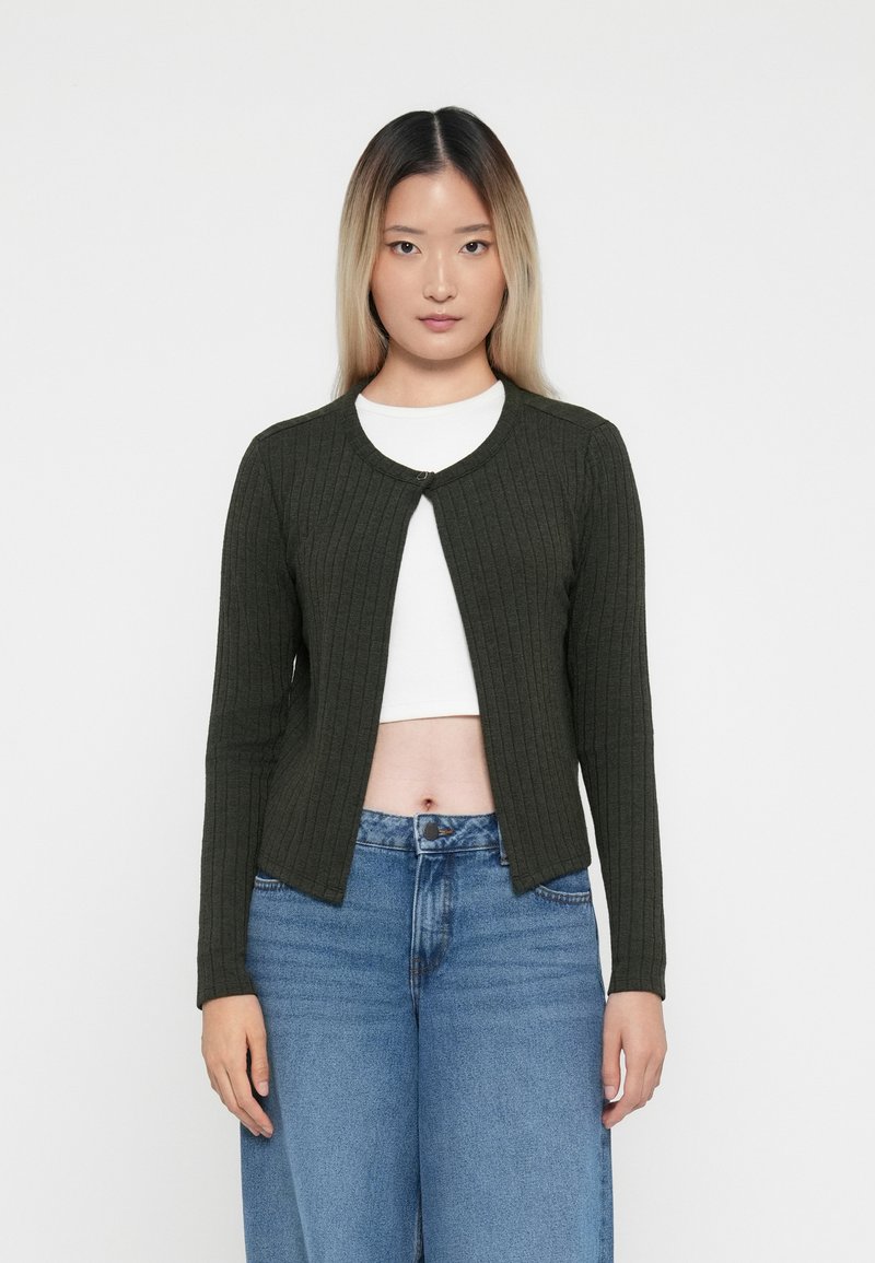 Olivengrønn ribbestrikket cardigan med rund hals, frontknappingslukking og lange ermer, parret med høyt liv blå denim jeans.