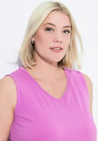 Top senza maniche rosa con scollo a V; tessuto morbido e liscio con una leggera lucentezza; il modello presenta capelli biondo chiaro e un trucco sobrio.
