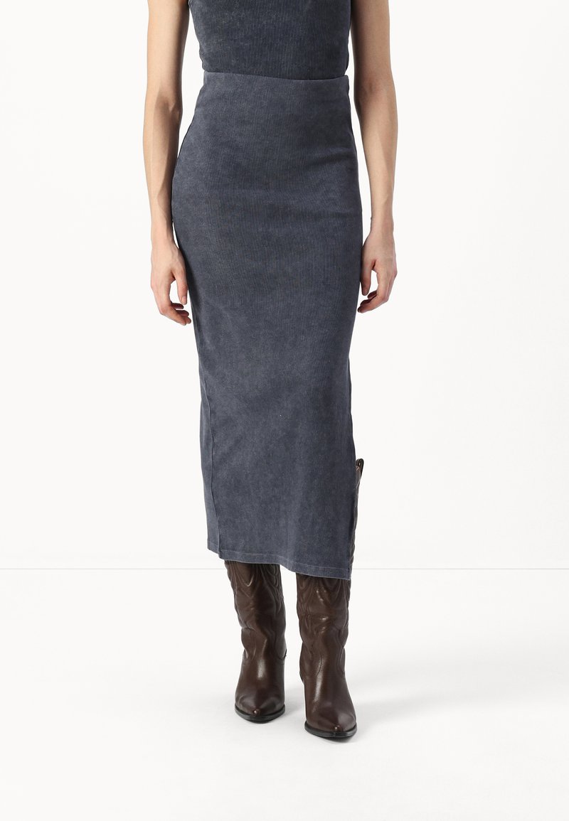 Σκούρο μπλε καμπαρντίνα μίντι φούστα με εφαρμοστή σχεδίαση, που διαθέτει λεία υφή και ευθεία σιλουέτα, συνδυασμένη με καφέ καουμπόικες μπότες.