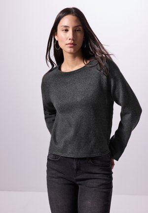 Dunkelgrauer Strickpullover, runder Ausschnitt, lange Ärmel, strukturierter Stoff und lässige Passform, kombiniert mit schwarzen Jeans. Schlichtes Design, keine Muster.