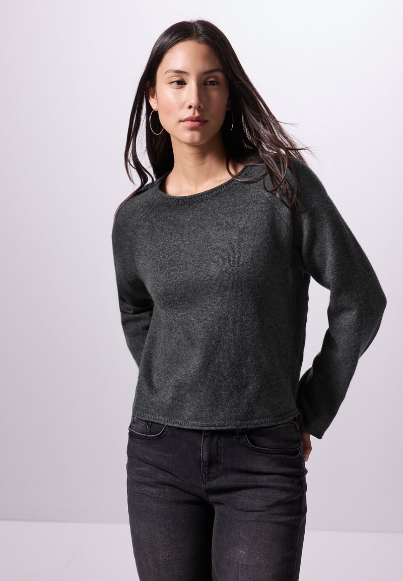 Dunkelgrauer Strickpullover, runder Ausschnitt, lange Ärmel, strukturierter Stoff und lässige Passform, kombiniert mit schwarzen Jeans. Schlichtes Design, keine Muster.