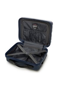 Valigia rigida blu navy con esterno rigato, fodera interna grigia, tasca con zip e cinghie incrociate per un'imballaggio sicuro.