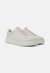 Weiße Leder-Sneaker mit runder Spitze, gepolstertem Kragen und weißer Sohle. Merkmale pinke Akzente an Zunge und seitlichem Logo. Glatte Textur.