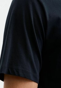 Granatowa bawełniana koszulka z okrągłym dekoltem, krótkim rękawem i gładką teksturą. Posiada subtelne przeszycia wzdłuż dołu.