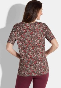 Short-sleeve floral top in brown with red and white flower patterns, rounded neckline, and relaxed fit, made from lightweight fabric.
