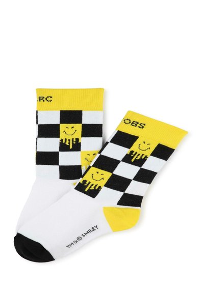 Chaussettes en damier noir et blanc avec des accents jaunes et des motifs de smileys ; fabriquées en tissu avec une texture douce et un bout noir contrastant.